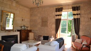 A living room with stone walls, a fireplace, and a large window with curtains. - House with character, Gardegan-et-Tourtirac (Gardegan-Et-Tourtirac)