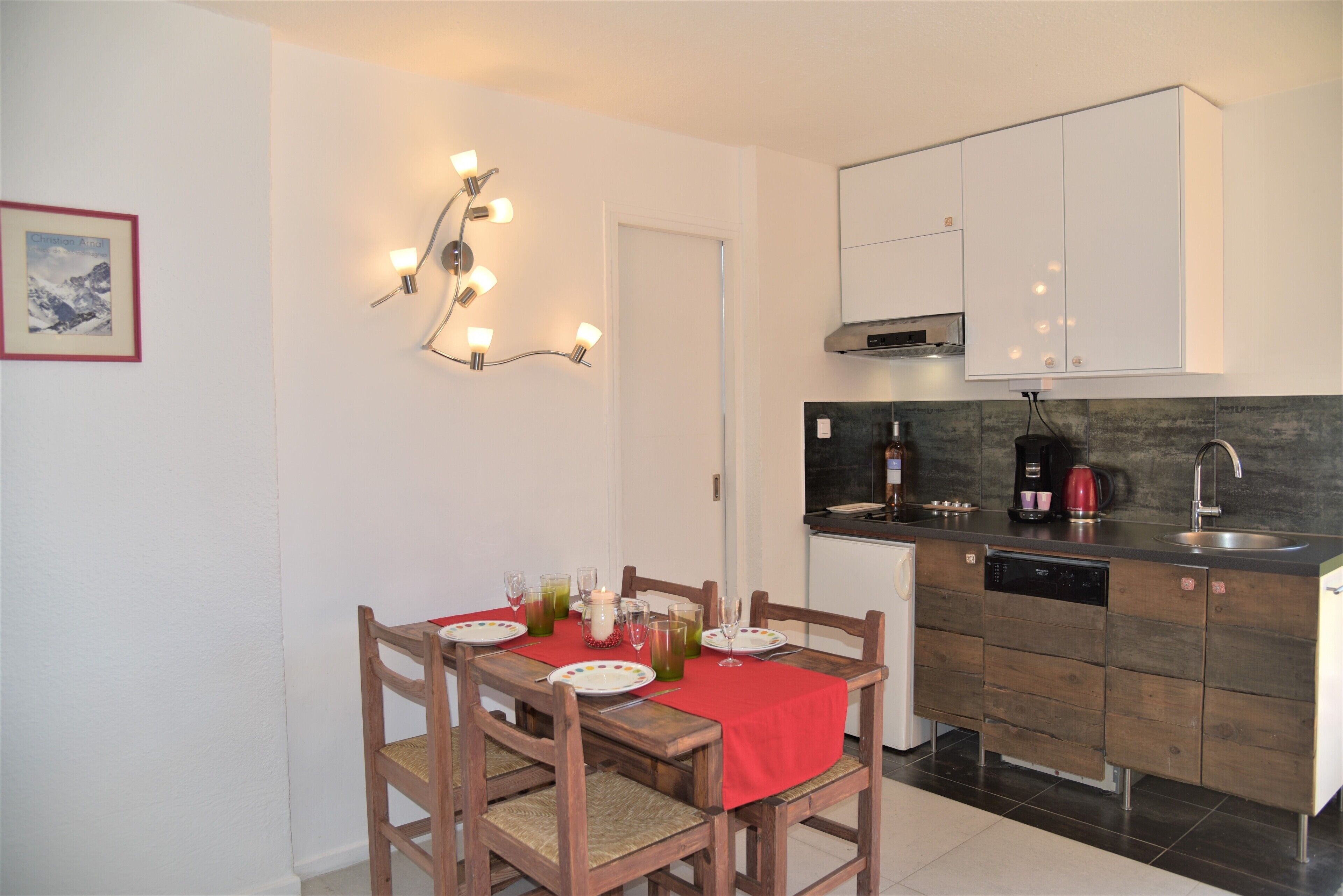 A compact kitchen with a dining area, equipped with a dishwasher, a coffee maker, and a sink.