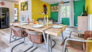 Un comedor con mesa de madera, sillas y refrigerador.
