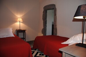 A room with two beds, a small table, a lamp, and a stone archway. - South Ardèche in Balazuc, listed site, Les Faysses self-catering gîte with charm and character (Balazuc)
