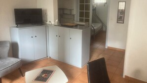 A compact living space with a kitchenette, a dining area, and a bedroom visible through an open door.