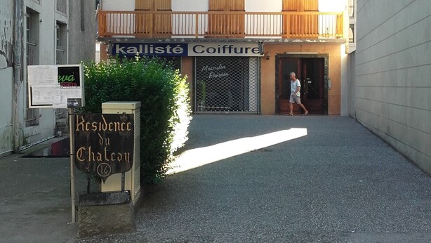 A building with multiple balconies, a sign for 'Residence du Chateau', and a storefront named 'kalliste Coiffure'.