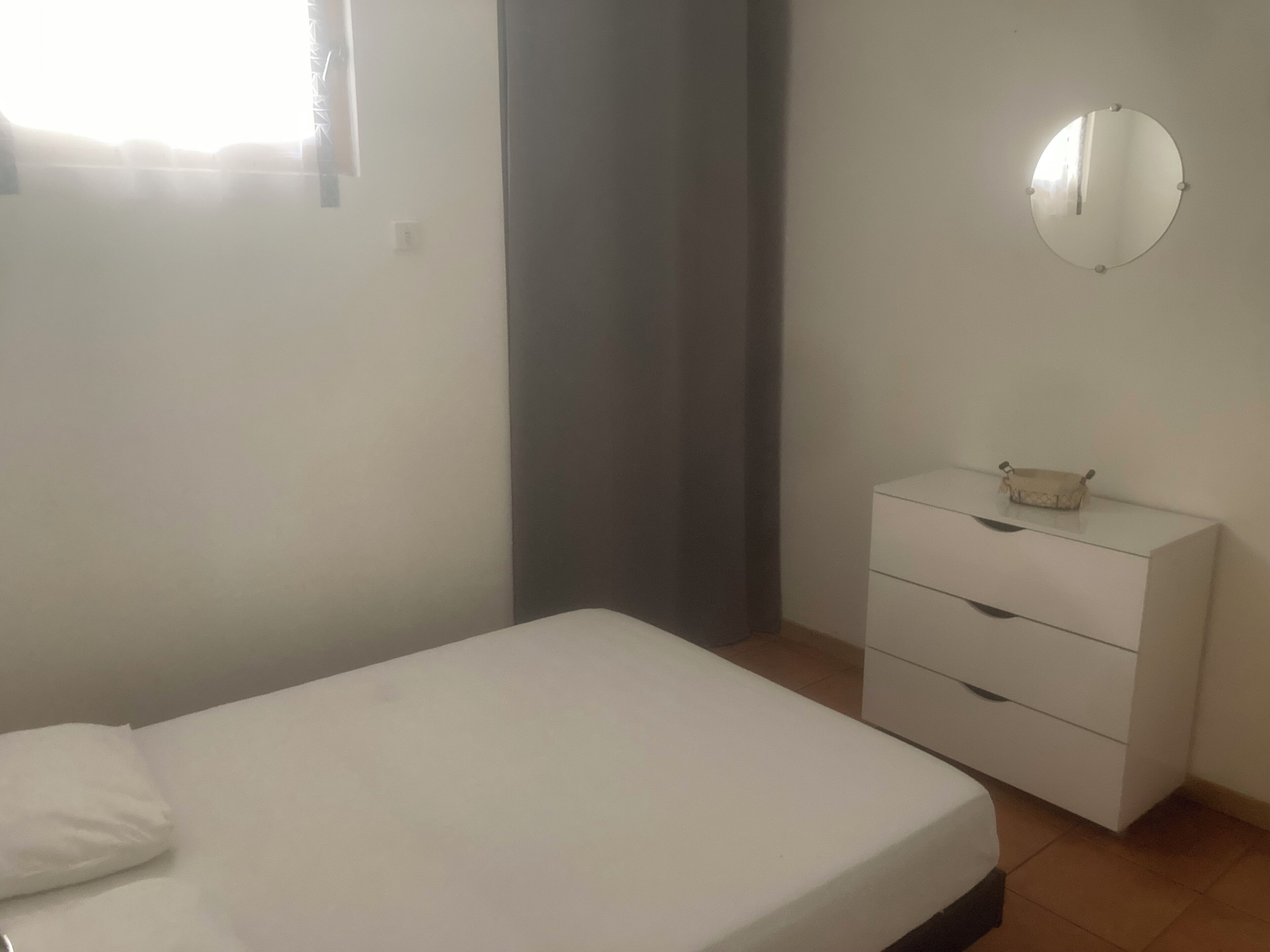 Une chambre à coucher avec un lit, une commode et un miroir au mur.