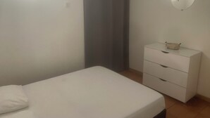 A bedroom with a bed, a dresser, and a mirror on the wall.