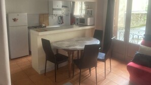 A compact kitchen with a dining table and chairs, a refrigerator, a microwave, and a coffee maker.