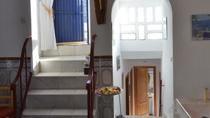 A staircase leading to a second floor with a chandelier, a dining area with a table and chairs, and a view of the outside through a window with blue curtains. - typical house in Spain in ALMERIA, Andalusia 6 people quiet (almeria)