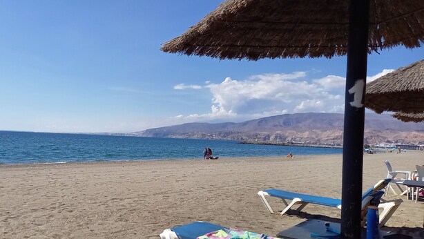 A beach with thatched umbrellas, lounge chairs, and a clear view of the sea and distant mountains. - typical house in Spain in ALMERIA, Andalusia 6 people quiet (almeria)