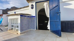 A patio with a blue chair, a tiled wall with a decorative pattern, and a blue door. - typical house in Spain in ALMERIA, Andalusia 6 people quiet (almeria)