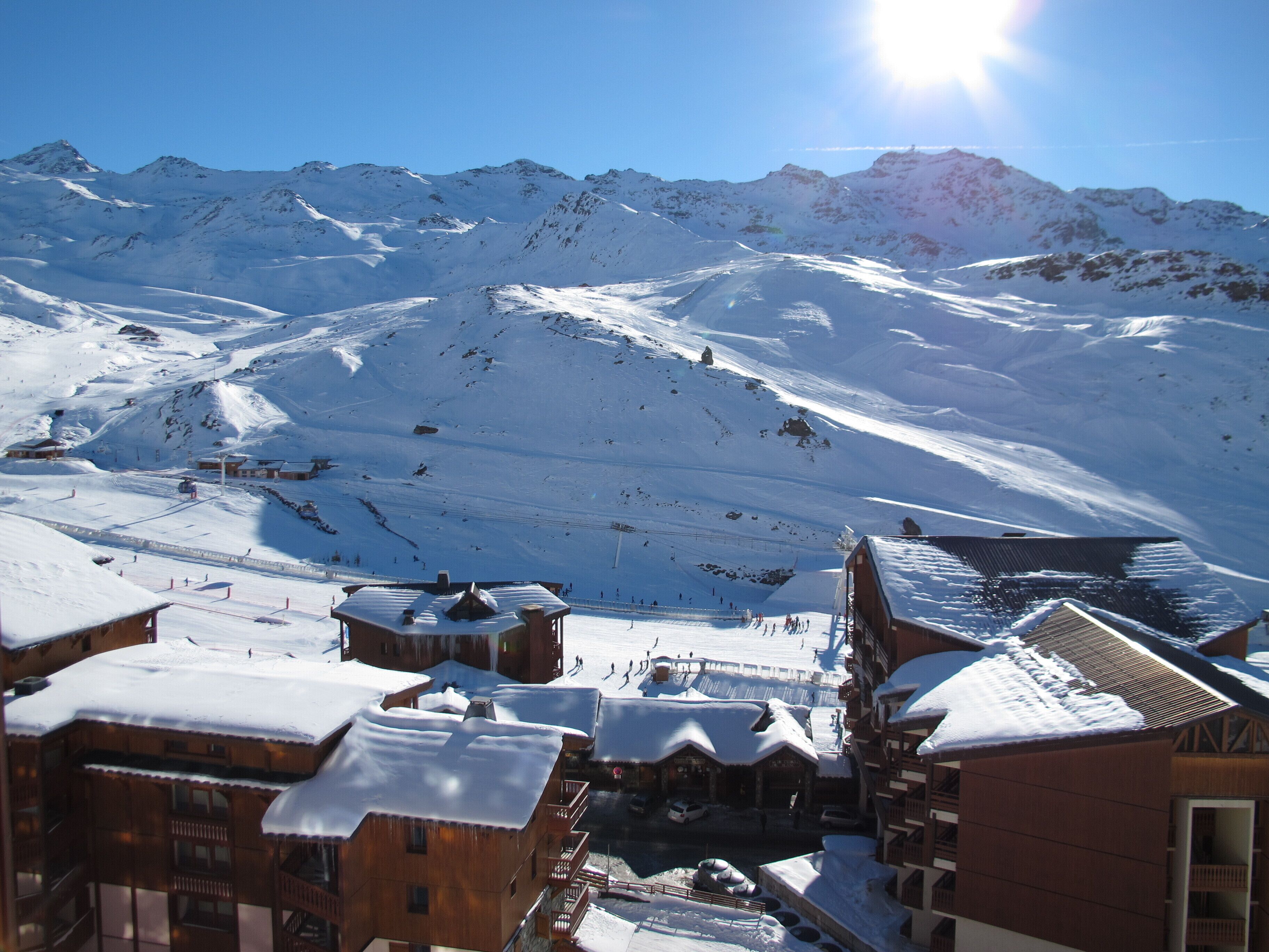 A snow-covered mountain village with wooden buildings and a ski slope.