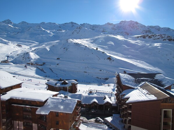 A snow-covered mountain village with wooden buildings and a ski slope.