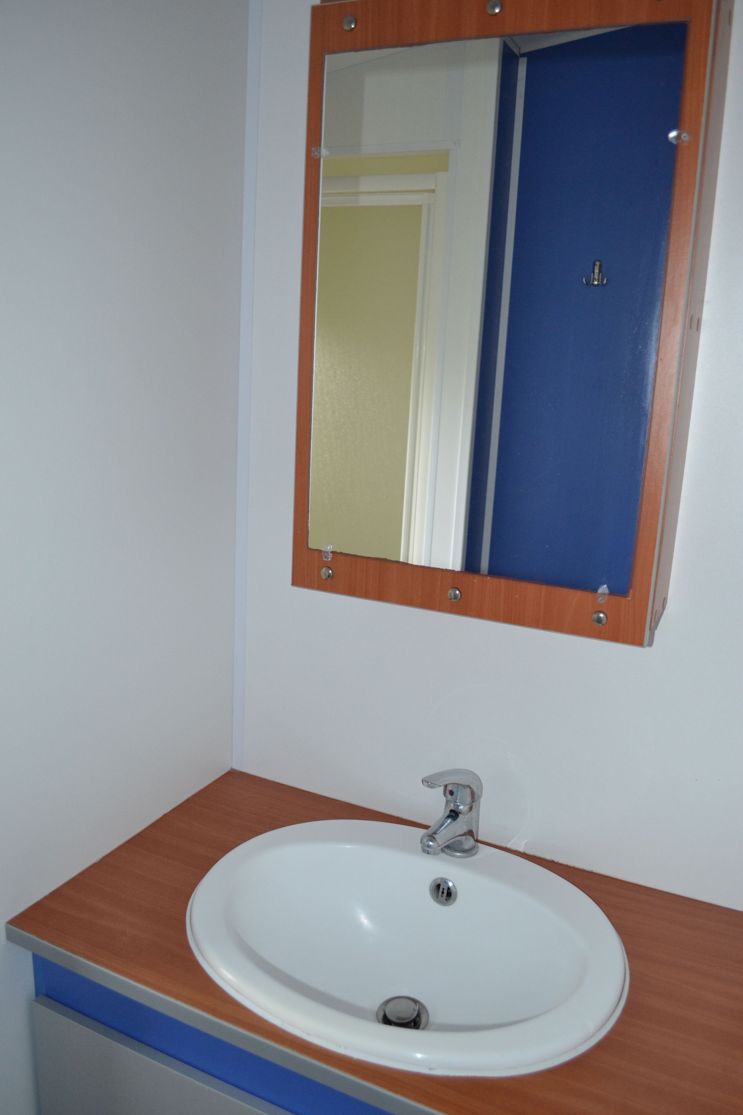 A bathroom with a white sink, a wooden countertop, and a mirror with a wooden frame.