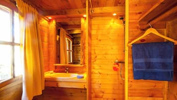 Un baño de cabaña de madera con lavamanos, espejo y toallero.