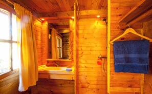 Un baño de cabaña de madera con lavamanos, espejo y toallero.