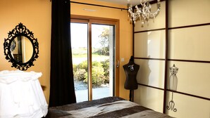 Une chambre à coucher avec un lit, une commode, un miroir et une vue sur l’extérieur.