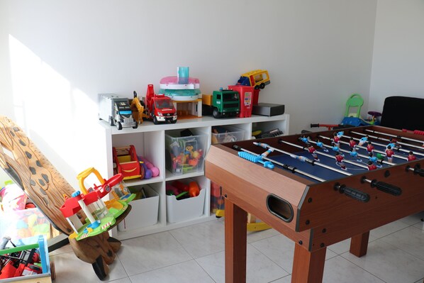 A room with a foosball table, shelves with toys, and a play area with a slide. - MAGNIFICENT NEW VILLA CLOSE BEACH WITH HEATED SWIMMING POOL (Erdeven)