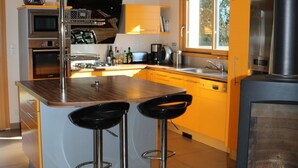 Une cuisine moderne dotée d’un îlot central, de tabourets de bar, d’une cuisinière et d’une fenêtre.
