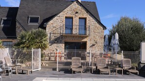 Un bâtiment en pierre doté d’une piscine, d’un espace extérieur aménagé pour s’asseoir et d’une terrasse clôturée.