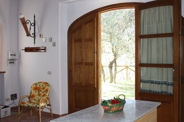 A room with a wooden door, a wicker chair, a marble countertop, and a basket. - The Bricks's Oven (Capannori)