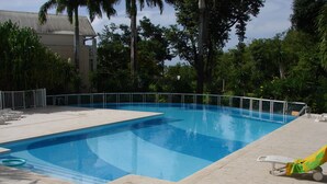 Una piscina rectangular con un borde empedrado y una barandilla metálica.