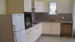A compact kitchen with white cabinets, a built-in oven, a sink, and a window above the countertop. - Vacation Rental in Cambo-Les-Bains: 2-room, air-conditioned, fully equipped—panoramic view. (Cambo-Les-Bains)