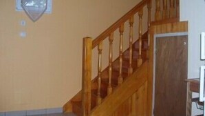 A wooden staircase with a handrail, a door at the bottom, and a window with a protective screen on the wall. - Vacation Rental in Cambo-Les-Bains: 2-room, air-conditioned, fully equipped—panoramic view. (Cambo-Les-Bains)