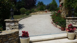 Un chemin de pierres mène à un bâtiment doté d’un mur en pierre et agrémenté de plantes en pot.