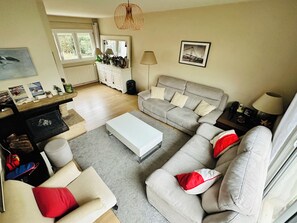 Uma sala de estar com sofá, poltronas, mesa de centro, lareira e área de refeições.
