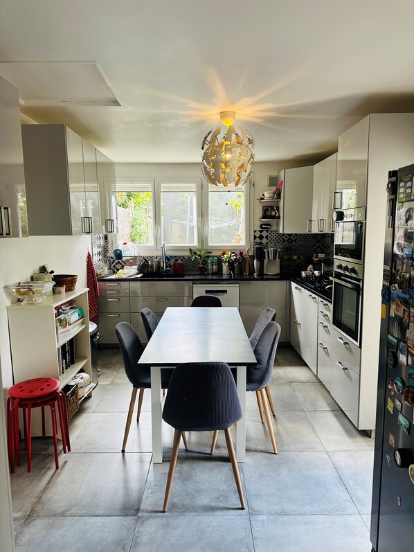 Uma cozinha moderna com ilha central, armários brancos e uma área de jantar com mesa e cadeiras.