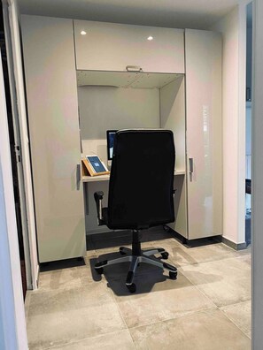 Um espaço de escritório moderno com uma cadeira de escritório preta, uma mesa com computador e um painel de vidro.
