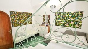 Ein Schlafzimmer mit einem Bett, einem Schminktisch und zwei an der Wand hängenden Bildern.