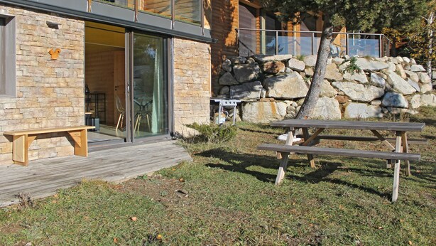 Een modern gebouw met een gevel van natuursteen, grote ramen en een houten terras.