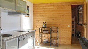 Een keuken met houten wanden, een roestvrijstalen fornuis en een metalen plank met keukengerei.