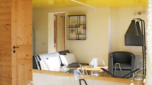 Een moderne kamer met een houten deur, een bank met wit en zwart gevulde kussens, een zwarte stoel, een klein tafeltje met een glas erop, en een zwarte vloerlamp.