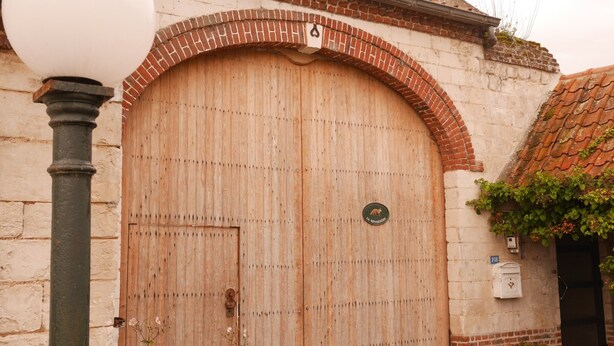 A large wooden door with a brick archway, a street lamp, and a small sign with a kangaroo logo.