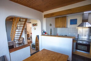 A kitchen with wooden beams, a stainless steel oven, and a tiled backsplash.