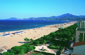 Ein Strand mit freiem Blick auf das Meer und Berge im Hintergrund.