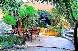 Ein Garten mit Steinmauer, einer Holzbank und einem Tisch mit Stühlen.