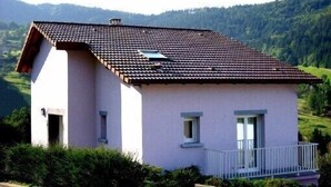 A single-story house with a tiled roof, a balcony, and a small window. - Renovated stone house, classified 3 stars between La Bresse and Gérardmer (Basse-Sur-Le-Rupt)