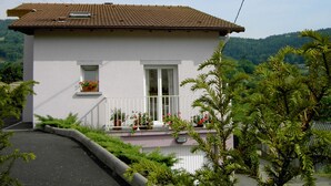 A two-story house with a tiled roof, white exterior walls, and a balcony with potted plants. - Renovated stone house, classified 3 stars between La Bresse and Gérardmer (Basse-Sur-Le-Rupt)