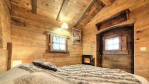 Une pièce de style cabane en bois, avec un lit, deux fenêtres et une porte.