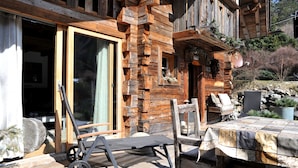 Une cabane en bois dotée d’une terrasse, de meubles d’extérieur et d’une grande porte-fenêtre coulissante.