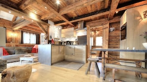L’intérieur d’un chalet rustique est agrémenté d’un plafond en bois, d’un coin cuisine équipé d’appareils modernes, d’une table à manger et d’un espace salon confortable.