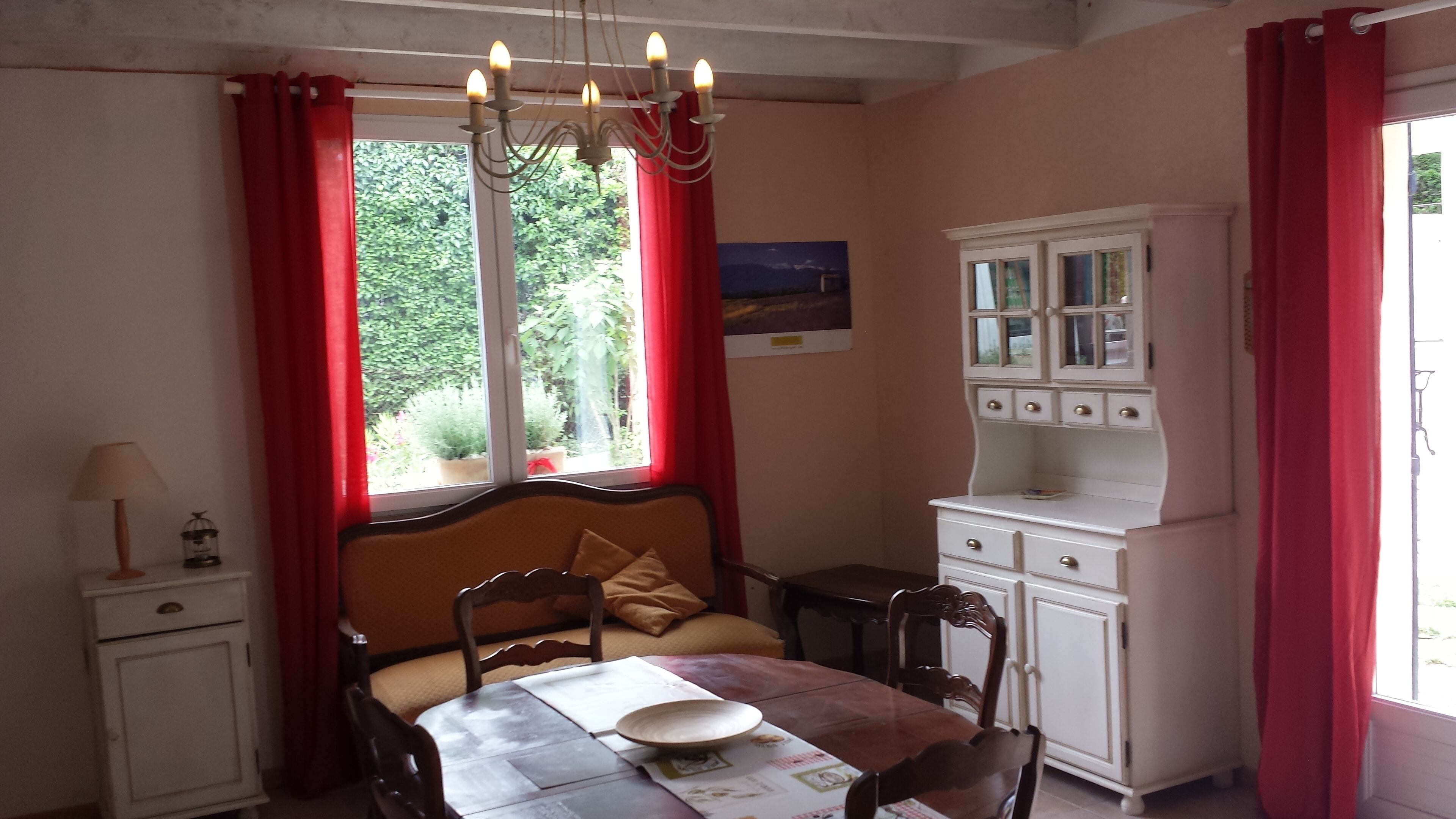 A bedroom with a bed, a table, a cabinet, and a window with curtains.