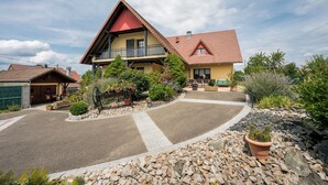 A two-story house with a red roof, a balcony, and a driveway leading to the entrance. - Large and beautiful detached house in a quiet and relaxing setting (Ruederbach)