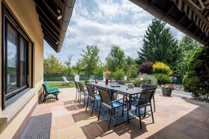 An outdoor patio with a table and chairs, a bench, and potted plants.