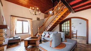 A spacious living room with a wooden staircase, a sofa set, and a chandelier. - Large and beautiful detached house in a quiet and relaxing setting (Ruederbach)