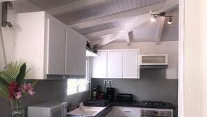 A compact kitchen with white cabinets, a microwave, a sink, a stove, and a small oven. - VILLA WITH PRIVATE POOL & GARDEN (8 PEOPLE) IN ST FRANCOIS GUADELOUPE (saint françois)