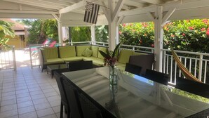 A covered outdoor seating area with a glass table, cushioned chairs, and a sofa. - VILLA WITH PRIVATE POOL & GARDEN (8 PEOPLE) IN ST FRANCOIS GUADELOUPE (saint françois)