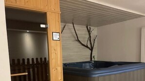 Ein Zimmer mit Holztür, weißer Wand, einer Zweigdekoration und einer blauen Whirlwanne.
