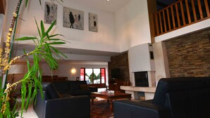 Ein geräumiges Wohnzimmer mit Kamin, Treppe und Kunstwerken an den Wänden.